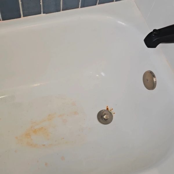 Bathtub with rust stains and slight discoloration near the drain.