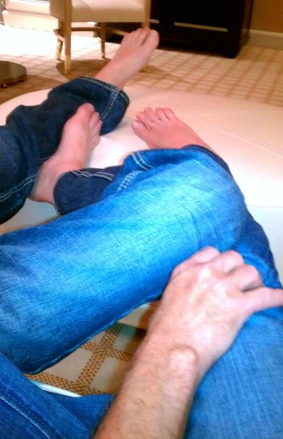 Man and woman in blue jeans entwine legs watching TV
