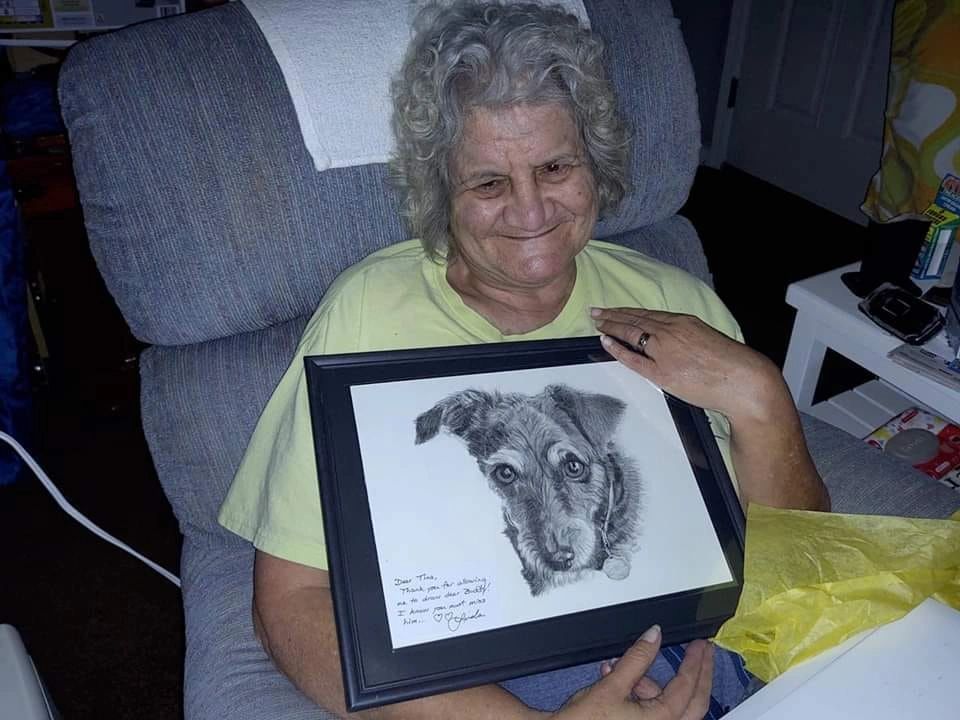 An older woman holding a framed custom pet portrait by Linda's Pet Portraits.