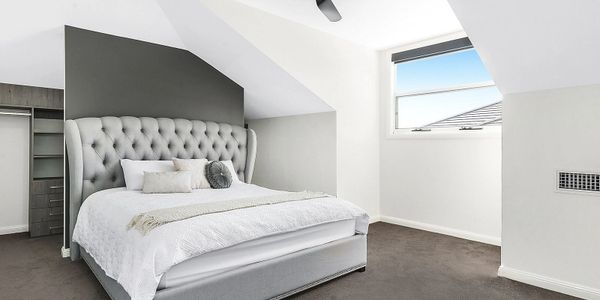 Modern bedroom with a grey tufted bed and sloped ceilings.