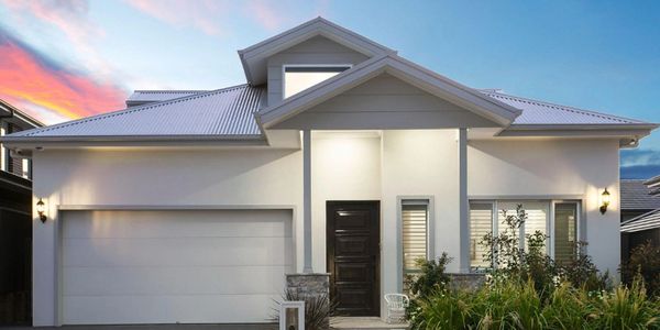 Modern white house with a large garage and well-lit entrance at sunset.