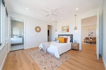 Bright bedroom with wooden floor, cozy bed, and modern bathroom access.