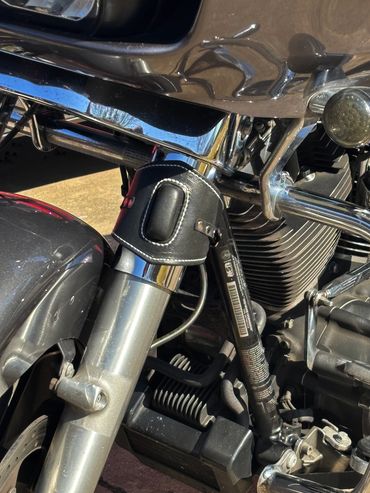 Close-up of chrome engine details with a black leather cup holder for drinks.