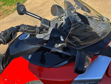 Close-up of a red and black motorcycle with handlebar and windshield details.