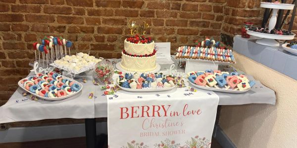 Berry-themed bridal shower dessert table with cake and treats.