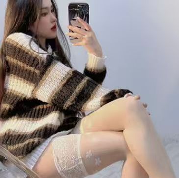 Woman in striped sweater taking a mirror selfie.