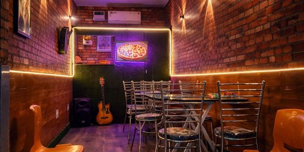 Cozy, dimly lit room with brick walls, musical instruments, and seating.