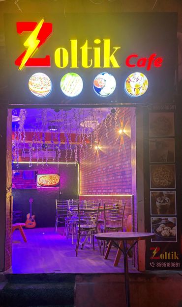Zoltik Cafe entrance with vibrant lighting and seating.