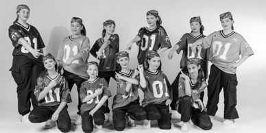 A group of young dancers in colorful jerseys and bandanas posing confidently.