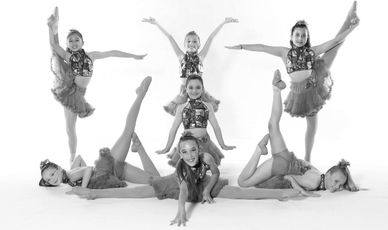Young girls in colorful dance costumes striking coordinated poses.