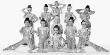 A group of young dancers in gold and silver costumes posing together.