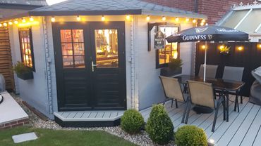 Cozy backyard bar setup with string lights and outdoor seating under a Guinness umbrella.