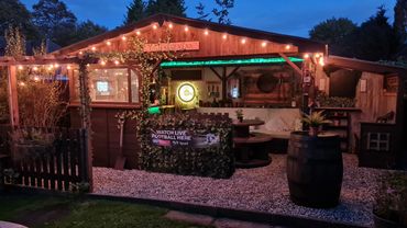 Cozy backyard bar with string lights and football signage at dusk.