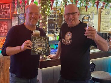 Two men celebrating with drinks in a cozy, decorated pub.