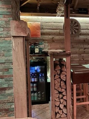 Cozy wooden home bar with cushioned seating and a dartboard.