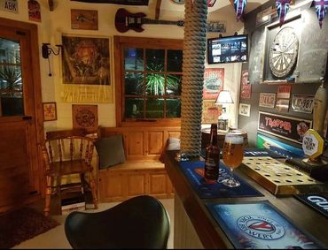 Cozy pub corner with wooden furniture, a dartboard, and beer on the bar counter.