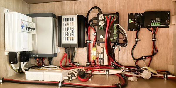 Neatly organized electrical wiring and control panels inside a wooden cabinet.