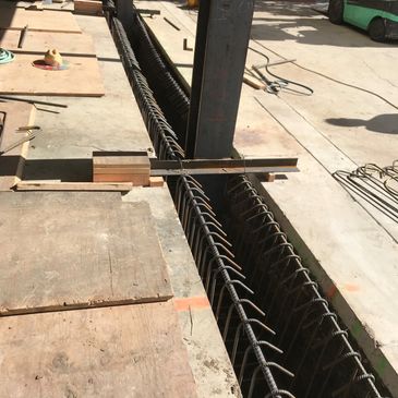Construction site with steel reinforcement and a worker in the background.