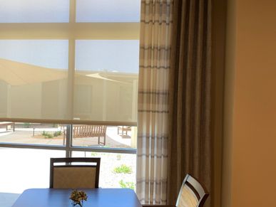 Drapery panels with two different fabrics and remote solar shade in a commercial dining room.