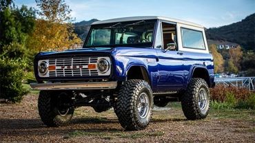 Classic blue Ford Bronco with off-road tires parked outdoors.