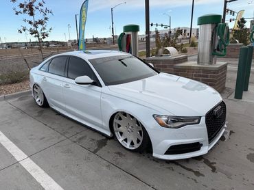 White Audi sedan with lowered suspension and large custom wheels parked at a car wash.