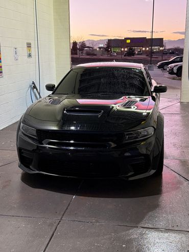 Black sports car parked in a wash bay at dusk.