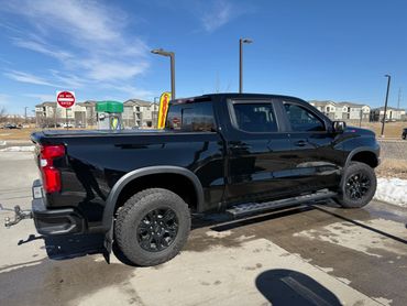 Black pickup truck parked near a car wash under a clear blue sky.