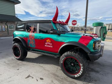 Custom off-road vehicle with devil-themed design and large tires.