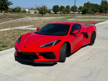 Red sports car parked on a sunny day in a suburban area.