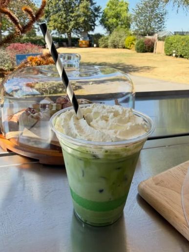 Iced matcha latte with whipped cream and a striped straw.