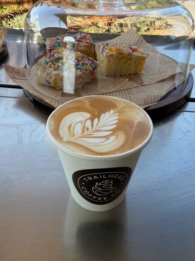 Latte in a white cup with pastries in the background.