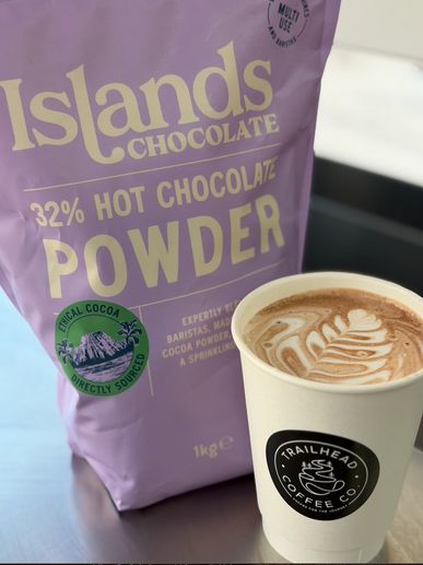 Hot chocolate powder and a coffee cup with latte art.