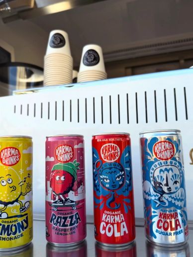 Four colorful Karma Drinks cans lined up on a counter.