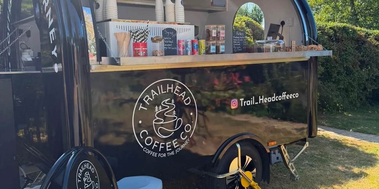 Outdoor mobile coffee cart with sunny backdrop.
