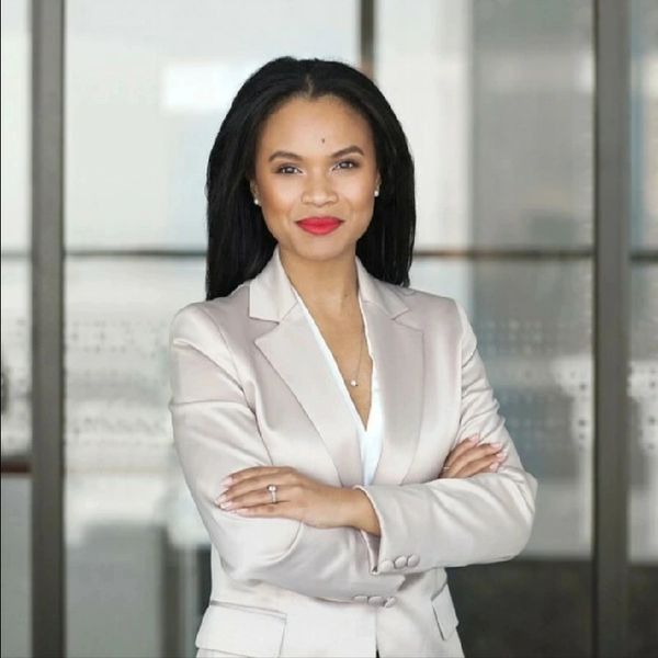 Confident woman in beige suit with arms crossed.