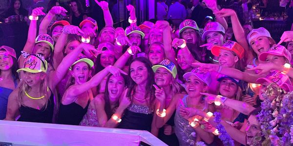 Bat mitzvah kids posing with their freshly painted trucker hats along the birthday girl.