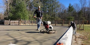 Concrete contractor operating a trowel machine while slick finishing or trowel finishing a barn conc