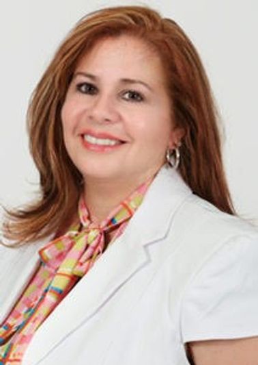 Smiling woman in white blazer with patterned scarf.