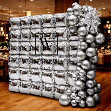 A silver balloon wall with spherical balloon decoration and spiked balloon accent.