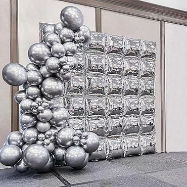 A silver balloon backdrop with a balloon cluster on the left side.