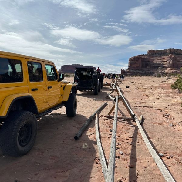 Jeeps lined up on a desert trail with rock formations.
