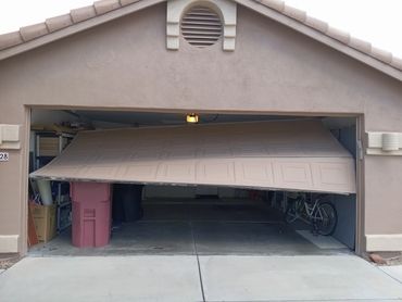 Partially open garage door with items inside including a bicycle and bins.