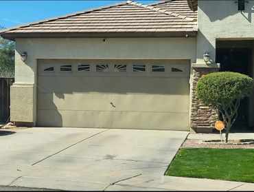 A beige garage door with small windows on a sunny day.
