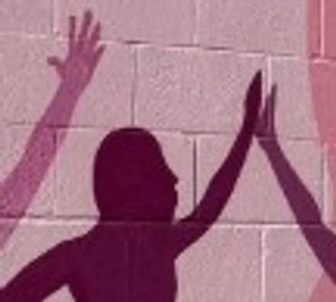 Clue #2: Silhouettes of hands and a head on a pink brick wall.
