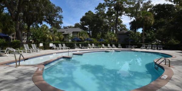 Sunny outdoor swimming pool with lounge chairs.