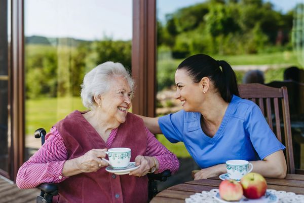The image shows two women, an elderly woman and a younger woman, sitting outdoors