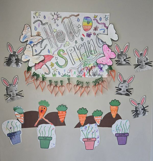 Colorful spring-themed wall decoration with drawings of carrots, butterflies, and bunny faces.