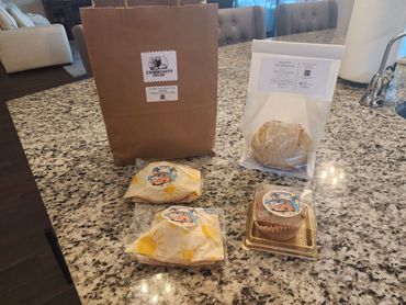 Bakery items including sourdough bread, muffins, and wrapped pastries on a kitchen counter.