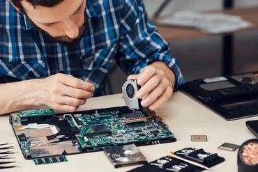 A technician repairing a Tv by replacing the cooling fan.