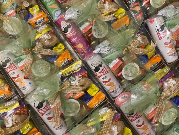 Gift boxes with snacks and Pringles cans wrapped with green ribbons.